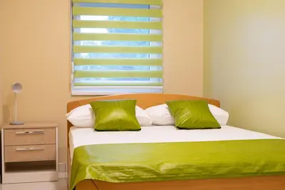 a bedroom with a bed with green sheets and a window at Jana apartmani in Novi Grad