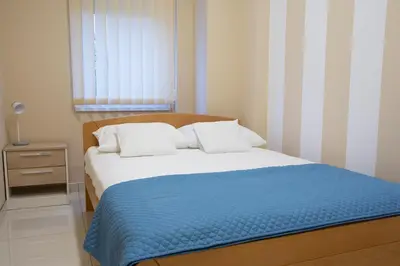 a bedroom with a bed with a blue blanket and a window at Jana apartmani in Novi Grad