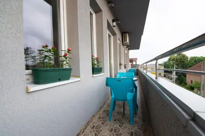 a balcony with blue chairs and potted plants at Jana apartmani in Novi Grad