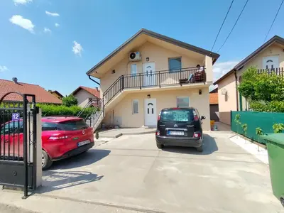two cars parked in a parking lot in front of a house at A1 - Airport Belgrade Apartment in Belgrade