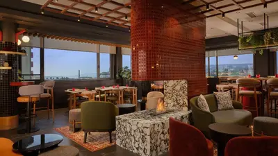 a restaurant with tables and chairs and large windows at Radisson RED Belgrade in Belgrade