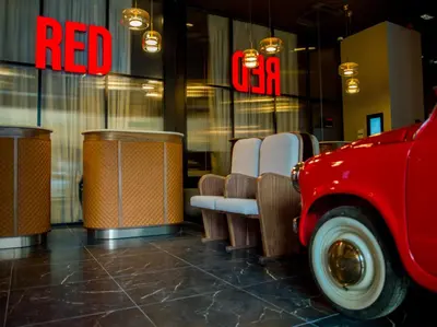 a red car parked in front of a restaurant with chairs at Radisson RED Belgrade in Belgrade