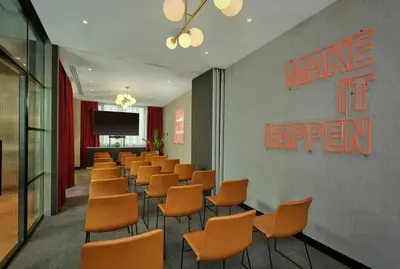 a waiting room with orange chairs and a screen at Radisson RED Belgrade in Belgrade