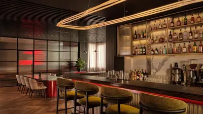 a bar with chairs and a counter with bottles at Radisson RED Belgrade in Belgrade