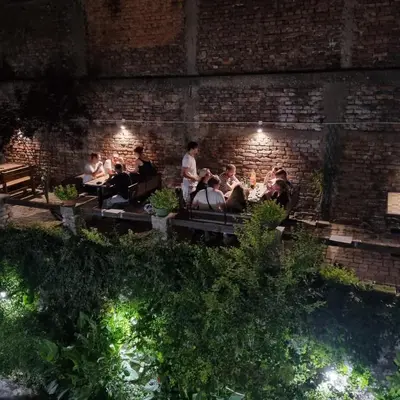 a group of people sitting on benches under a brick wall at Up Hostel in Belgrade