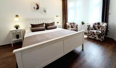 a bedroom with a large white bed and two chairs at GENIUS STUDIO in Belgrade