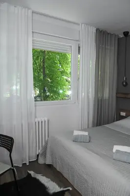 a bedroom with a bed and a window and a chair at Apartment GREEN in Belgrade