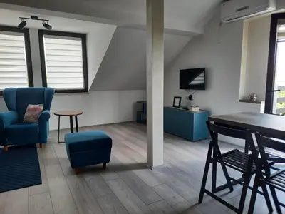 a living room with a table and a blue chair at Galerija Park 2 in Arandjelovac