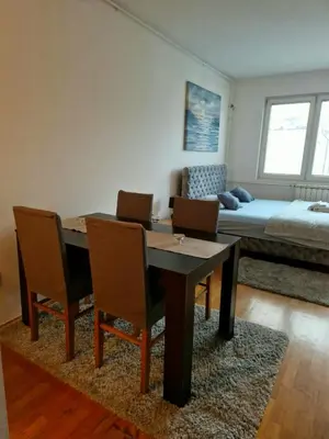 a dining room with a table and chairs and a bed at Anchy Apartment in Belgrade
