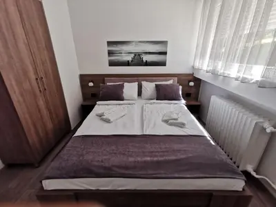 a bedroom with a bed with white sheets and pillows at Apartman PAVLOVIC 1 in Dedinje