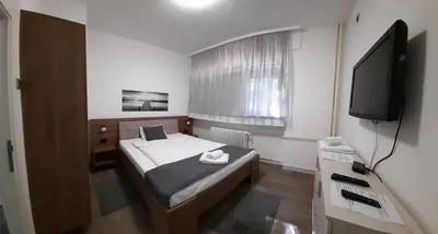 a small bedroom with a bed and a television at Apartman PAVLOVIC 1 in Dedinje