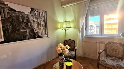 a living room with a table and a vase of flowers at Windows City Apartment in Belgrade