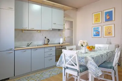 a kitchen with white cabinets and a table with chairs at Windows City Apartment in Belgrade