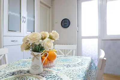 a table with a vase of flowers and oranges on it at Windows City Apartment in Belgrade