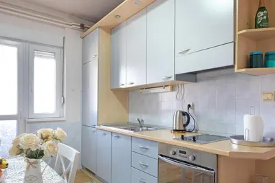 a kitchen with white cabinets and a vase of flowers at Windows City Apartment in Belgrade