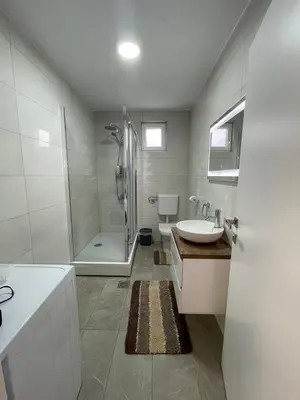 a white bathroom with a shower and a sink at LEDA Apartmani in Smederevo