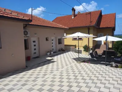 a patio with two umbrellas and chairs and a house at LEDA Apartmani in Smederevo
