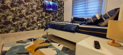 a bedroom with a bed and a tv on a wall at Apartman Green Garden Aranđelovac in Arandjelovac