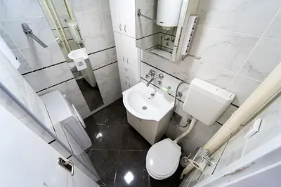 a white bathroom with a toilet and a sink at Apartman Šumice in Vračar (historical)