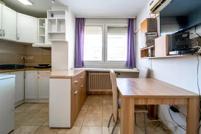 a small kitchen with a table and a table and a window at Apartman Šumice in Vračar (historical)
