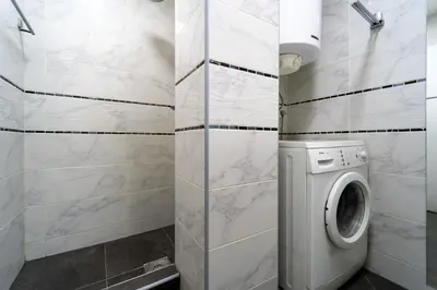 a white bathroom with a washing machine in it at Apartman Šumice in Vračar (historical)