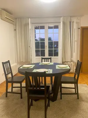 a dining room with a table and chairs and a window at Lord's Apartment in Belgrade