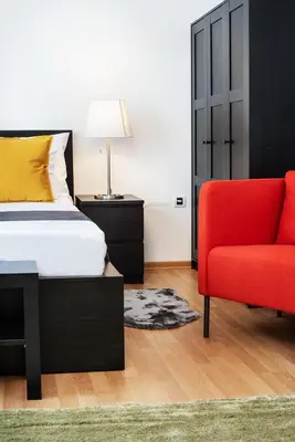 a bedroom with a bed and a red chair at Studio apartment Financial Park Belgrade in Belgrade