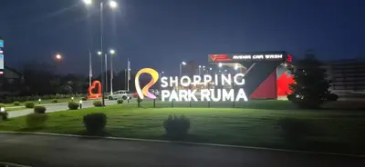 a large sign in a park at night at Apartman Bajka in Ruma
