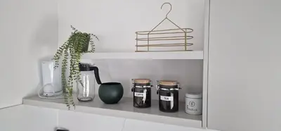 a shelf with jars and a plant on it at Apartman Bajka in Ruma