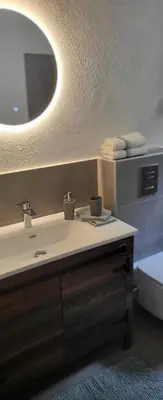 a bathroom with a sink and a mirror and a toilet at Apartman Bajka in Ruma