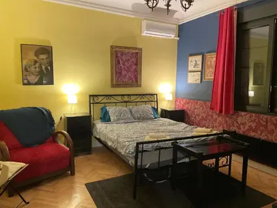 a bedroom with a bed and a red chair at Cosy studio apartment in a heart of the Belgrade in Belgrade