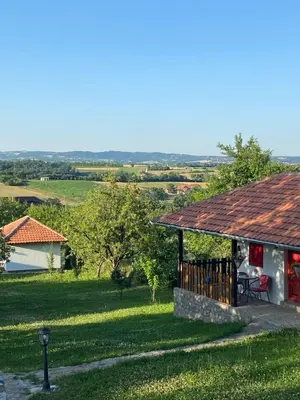 a house with a porch and a yard with a field at Bas u inat babarogama in Koraćica
