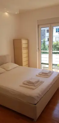 a bedroom with a bed with white sheets and a window at Vanja’s place in Dušanovac (historical)