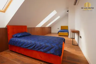 an attic bedroom with a bed and a desk at DeLux Center Apartments Inđija in Inđija