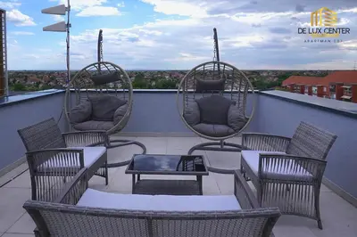 a patio with chairs and tables and swings on a roof at DeLux Center Apartments Inđija in Inđija