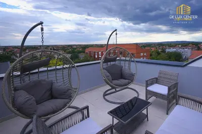 a balcony with two swing chairs and a table at DeLux Center Apartments Inđija in Inđija