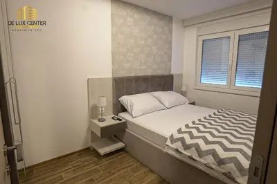 a small bedroom with a bed and a window at DeLux Center Apartments Inđija in Inđija