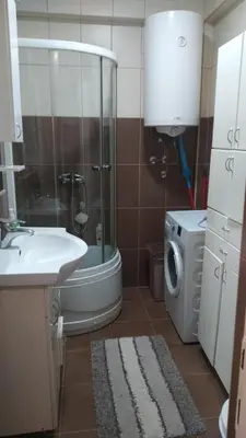 a bathroom with a shower and a sink and a washing machine at Relax 2 besplatan parking in Obrenovac