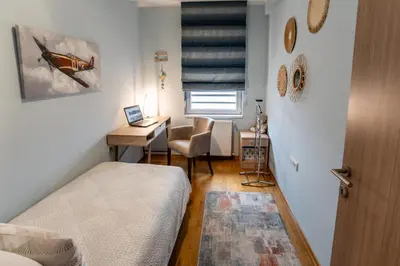 a bedroom with a bed and a desk and a chair at Apartman AuRa in Arandjelovac