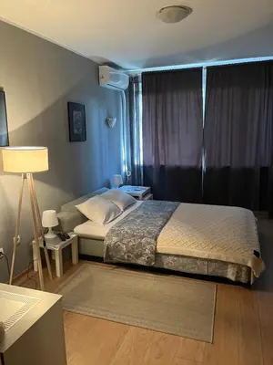 a bedroom with a bed and a lamp and a window at Grey in Belgrade