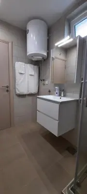 a white bathroom with a sink and towels at River Casa in Ledine