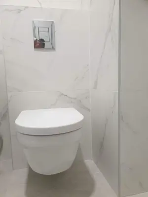 a white toilet in a bathroom with white marble walls at Minel cosy apartment in Belgrade