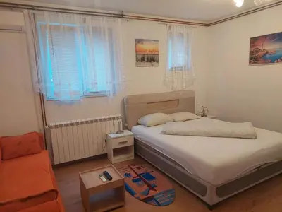 a small bedroom with a bed and a couch at Apartman Anastasija in Surčin