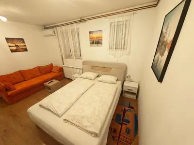 a small bedroom with a bed and a couch at Apartman Anastasija in Surčin