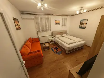 a small bedroom with a bed and a couch at Apartman Anastasija in Surčin