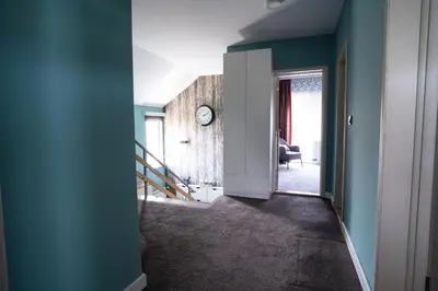 a hallway with blue walls and a clock on a wall at Family / Coworking Retreat Belgrade in Belgrade