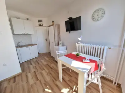 a small apartment with a table and a clock on the wall at Sunset in Belgrade
