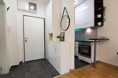 a kitchen with white cabinets and a large door at Martha apartments in Belgrade