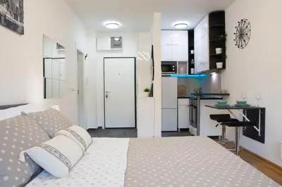 a bedroom with a large bed and a kitchen at Martha apartments in Belgrade