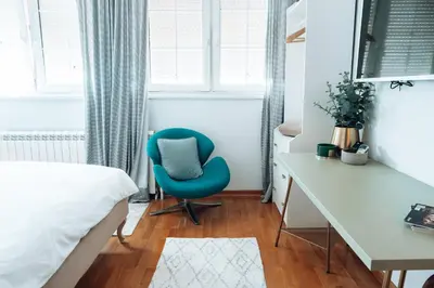 a bedroom with a blue chair and a desk at Zeus Nest Apartment in Belgrade